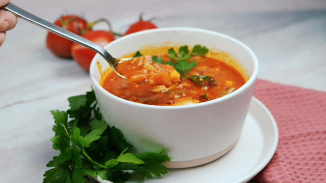 a person holding a spoon in a bowl of soup